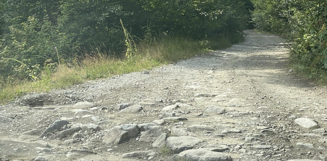 Gravel road with large rocks and holes in the foreground