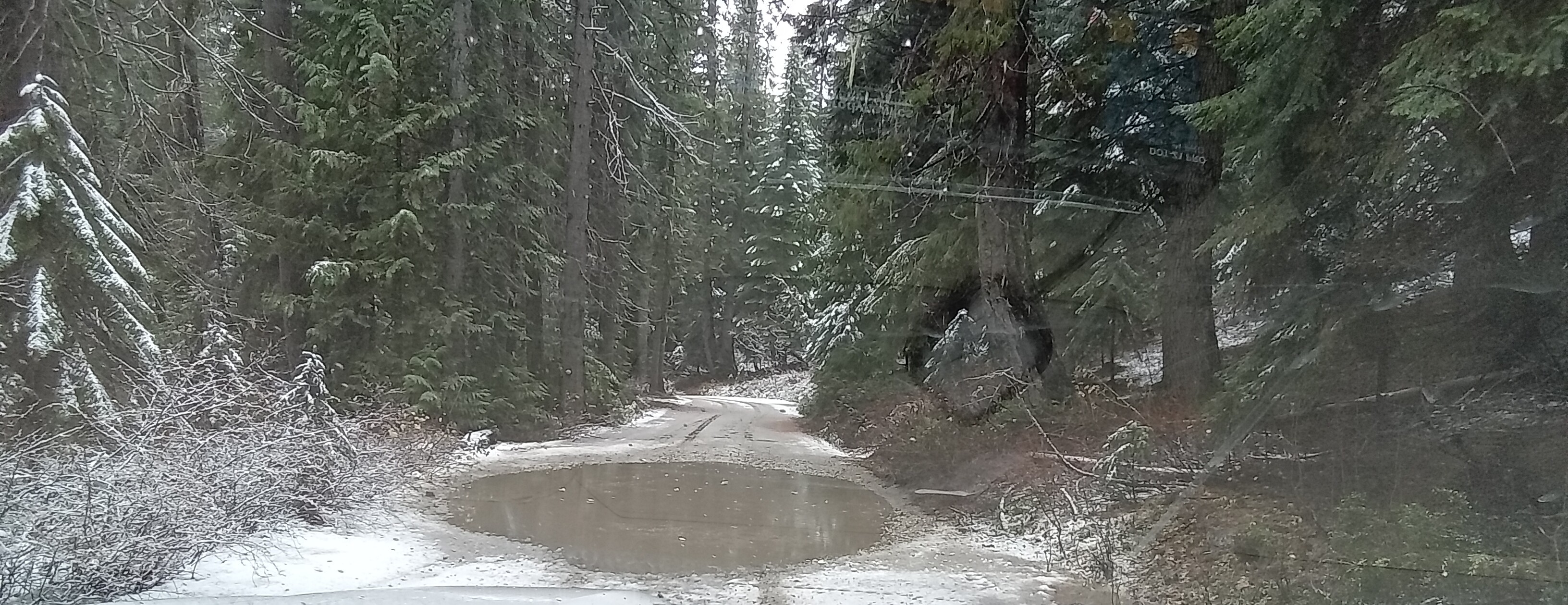 Pothole filled with water that spans the width of a road