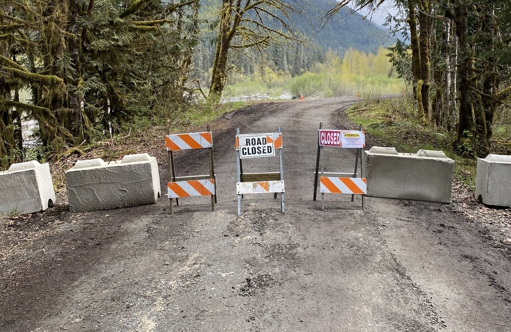 Road blocked by concrete barricades and "Road Closed" sign on easel