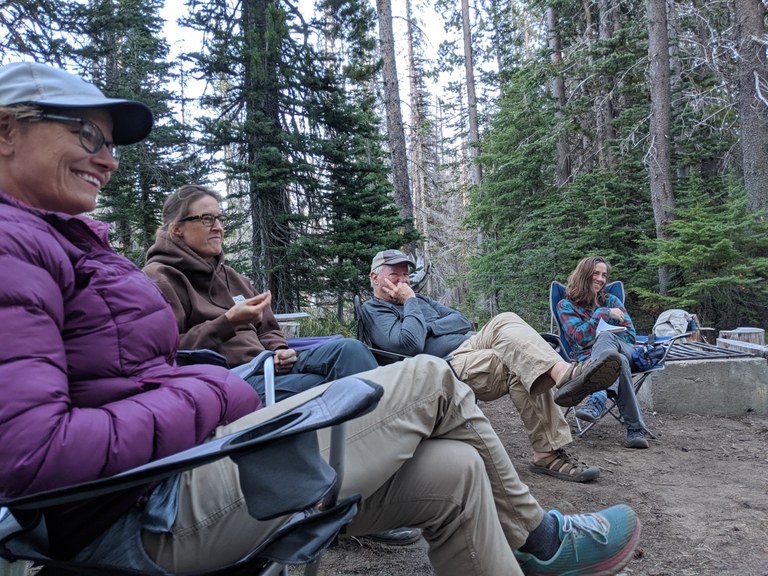 Volunteers sit in camp chairs and smile.