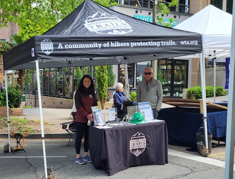 Two ambassadors stand under a WTA canopy at an outreach booth