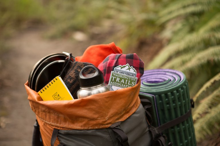 An open backpack overflowing with gear