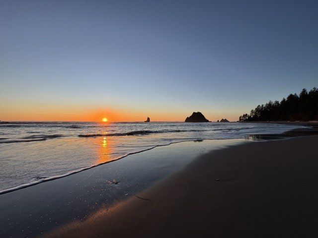 An orange sun sets below the Pacific Ocean near Toleak Point 