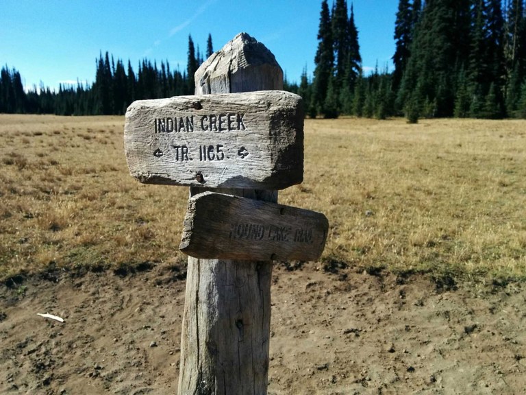 Sign in Blankenship Meadows A trail sign reading Indian Creek is in a large grassy meadow.