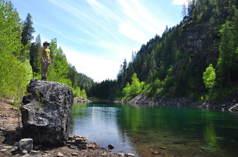 Hiker at Emerald Lake A hiker stands on a large rock to the left of a lake