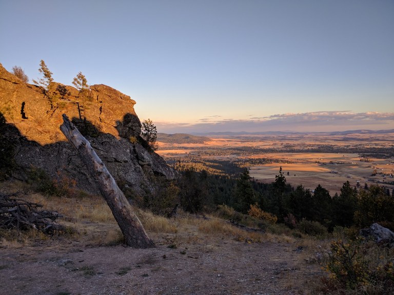 View from the summit with some exposed rock in the foreground and a valley in the distance. Photo by Suhleenah. 