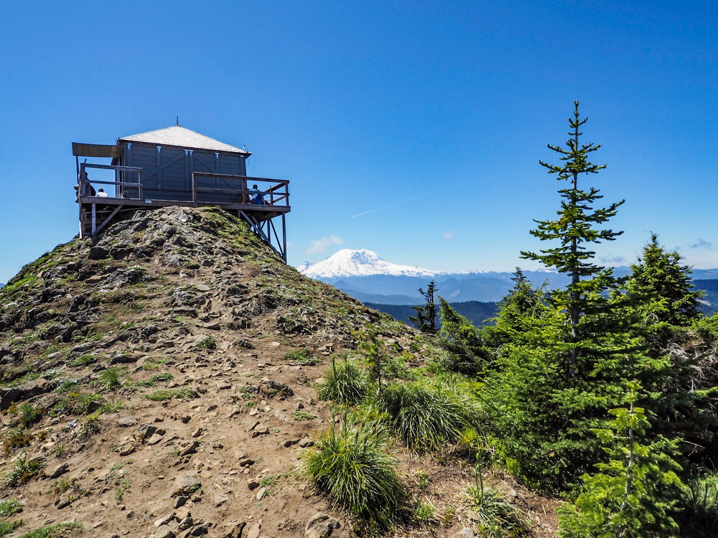Kelly Butte A fire lookout tower is perched on a rocky hill overlooking a forest filled valley.