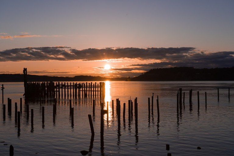 Old wooden piers sticking out of the water with the sunset in the background. 