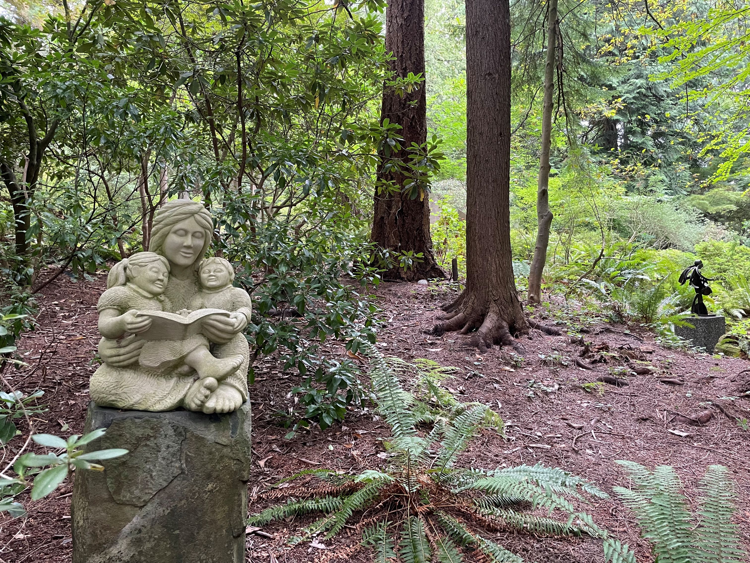 A status of an adult reading to two children at Big Rock Garden in Bellingham. Photo by trip reporter LizzyRN.