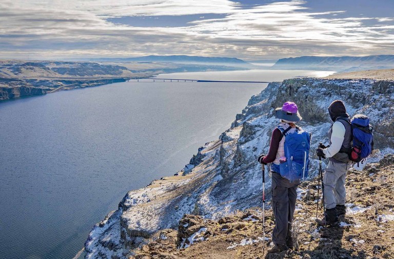 Two hikers look out on the Columbia River from high atop a frost encrusted rockface.