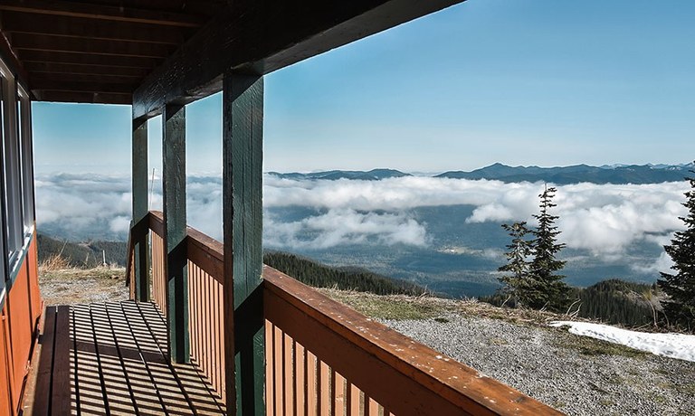 View of a forested valley from a cabin's porch.