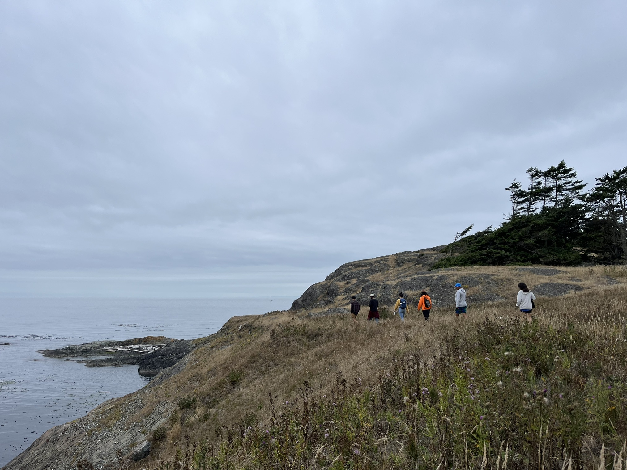 Hikers hiking along the bluff with views of the water at Iceberg Point. Photo by hikingwithlittledogs.