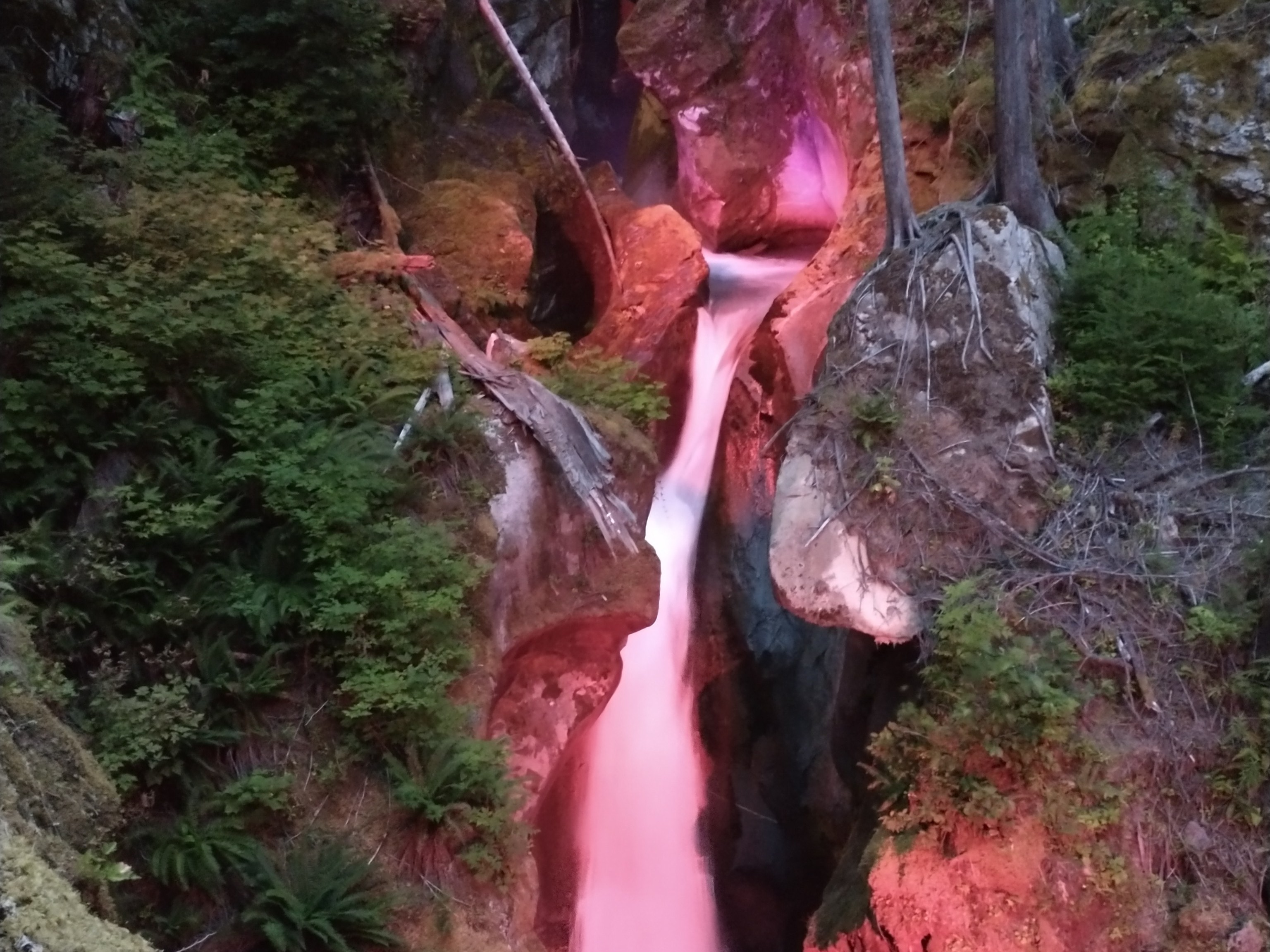Ladder Creek Falls. When the days are short and the darkness is heavy, getting outside may seem tougher than usual. But there are benefits to even getting outside for a little bit of time each day, and here are some hikes that can help you do that on these dark days. A red light illuminates Ladder Creek Falls. Photo by multivariablespace.