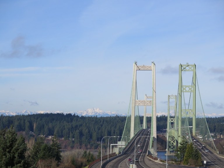 View west across the Tacoma Narrows Bridge with the Olympics peaking out. Photo by Erik Morgenstern. 