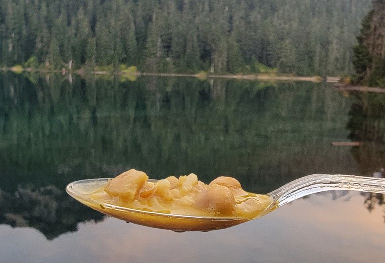 A spoonful of food is suspended before a lake.