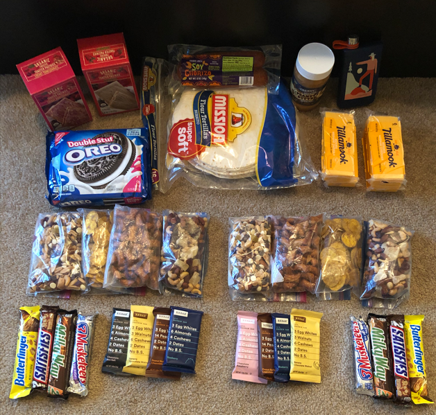 Several days worth of backpacking food are organized on the floor.