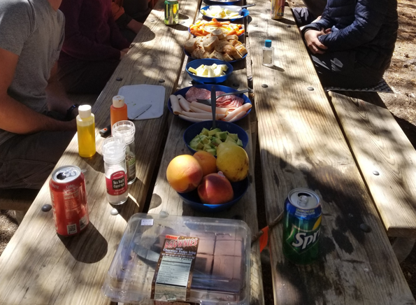 A series of dishes are aligned on a picnic table.