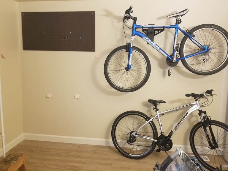 Bike racks really open-up floor space. Photo by Joseph Gonzalez. One bike is suspended on a wall with a rack. The other sites below it with a kickstand.