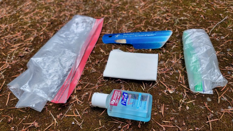 A traditional backcountry bathroom kit. You can slowly ween yourself into the bidet system only bringing a little bit of toilet paper on your next trip, aka TP roulette. Photo by Joseph Gonzalez Two ziploc bags, some toilet paper, a trowel and hand sanitizer sit side by side.