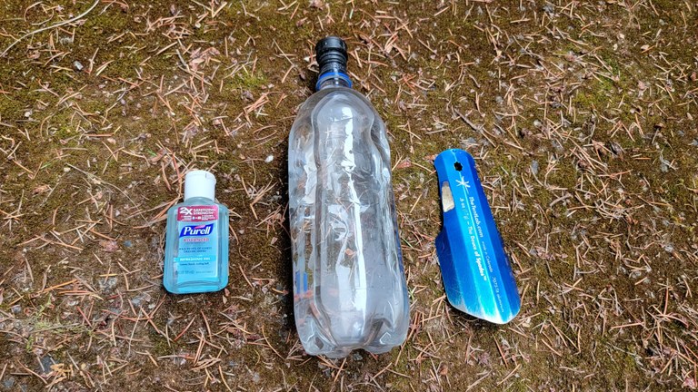 Hand sanitizer are optional, but highly recommended. Photo by Joseph Gonzalez A bottle of hand sanitizer, a water bottle with a bidet nozzle attached, and a trowel are laid side by side.