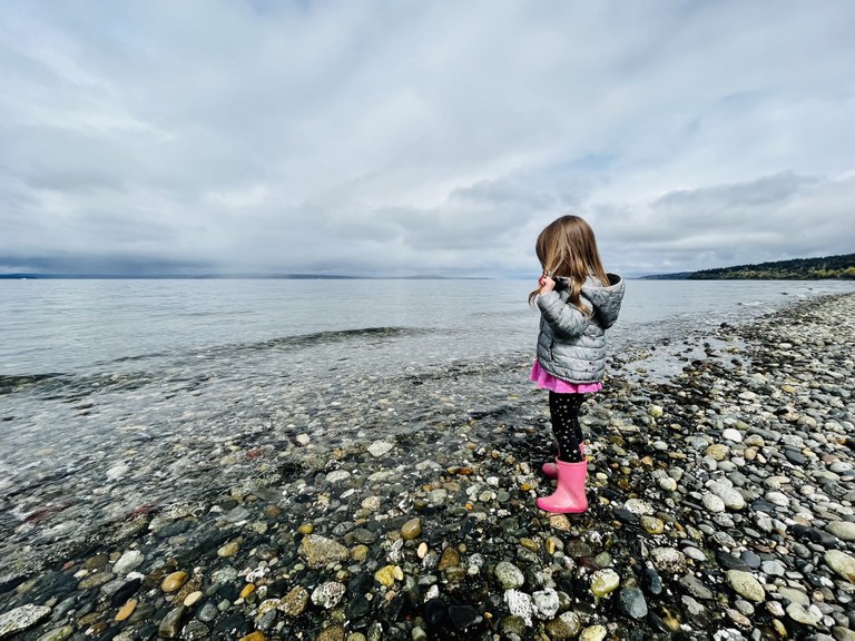 Tinker with filter options to make your image pop. Photo by Erika Haugen-Goodman. A child stands on the pebbly shore of a body of water and peers beneath the surface.