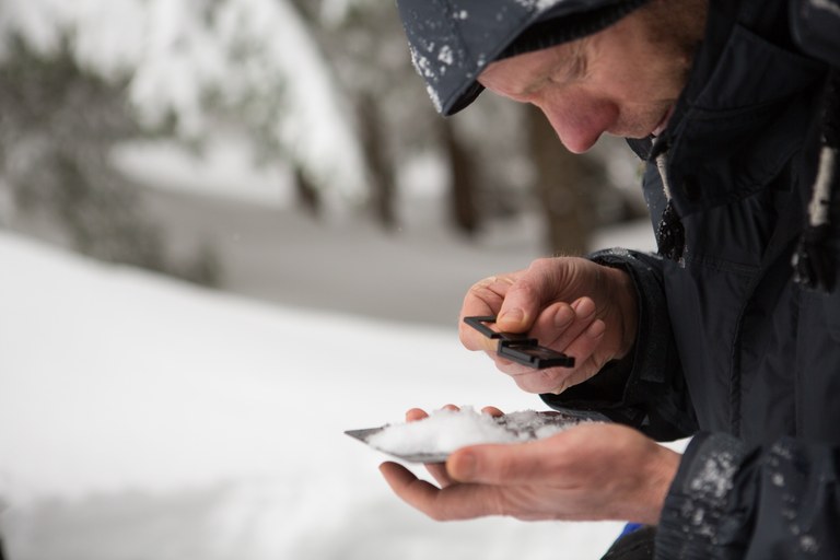 A man inspects a small pile of snow to determine avalanche conditions. 