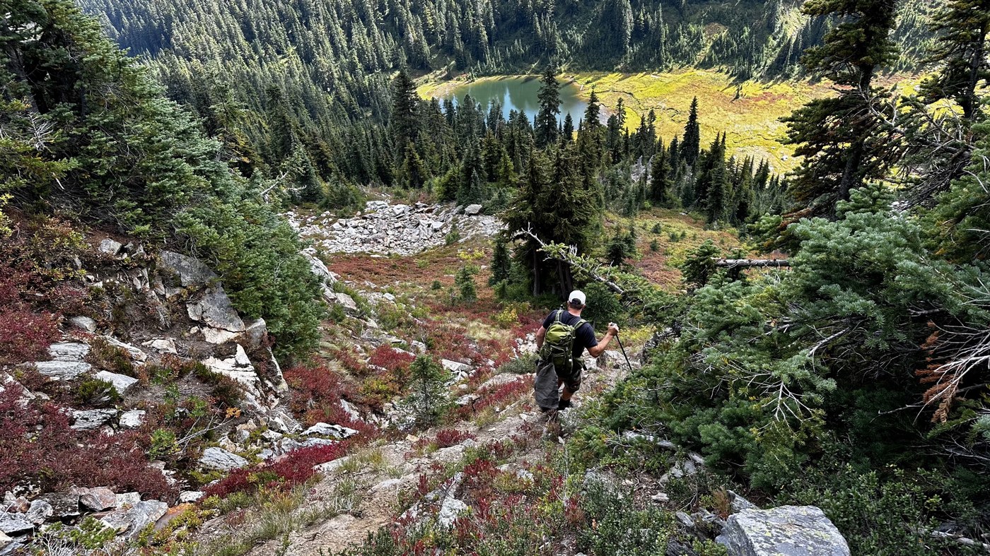 Scramble path by trip reporter Glen99 Hiker with a pole makes their way down a steep, rocky path towards a lake