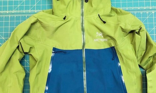 A green Arcteryx raincoat with a blue patch in the stomach area. 