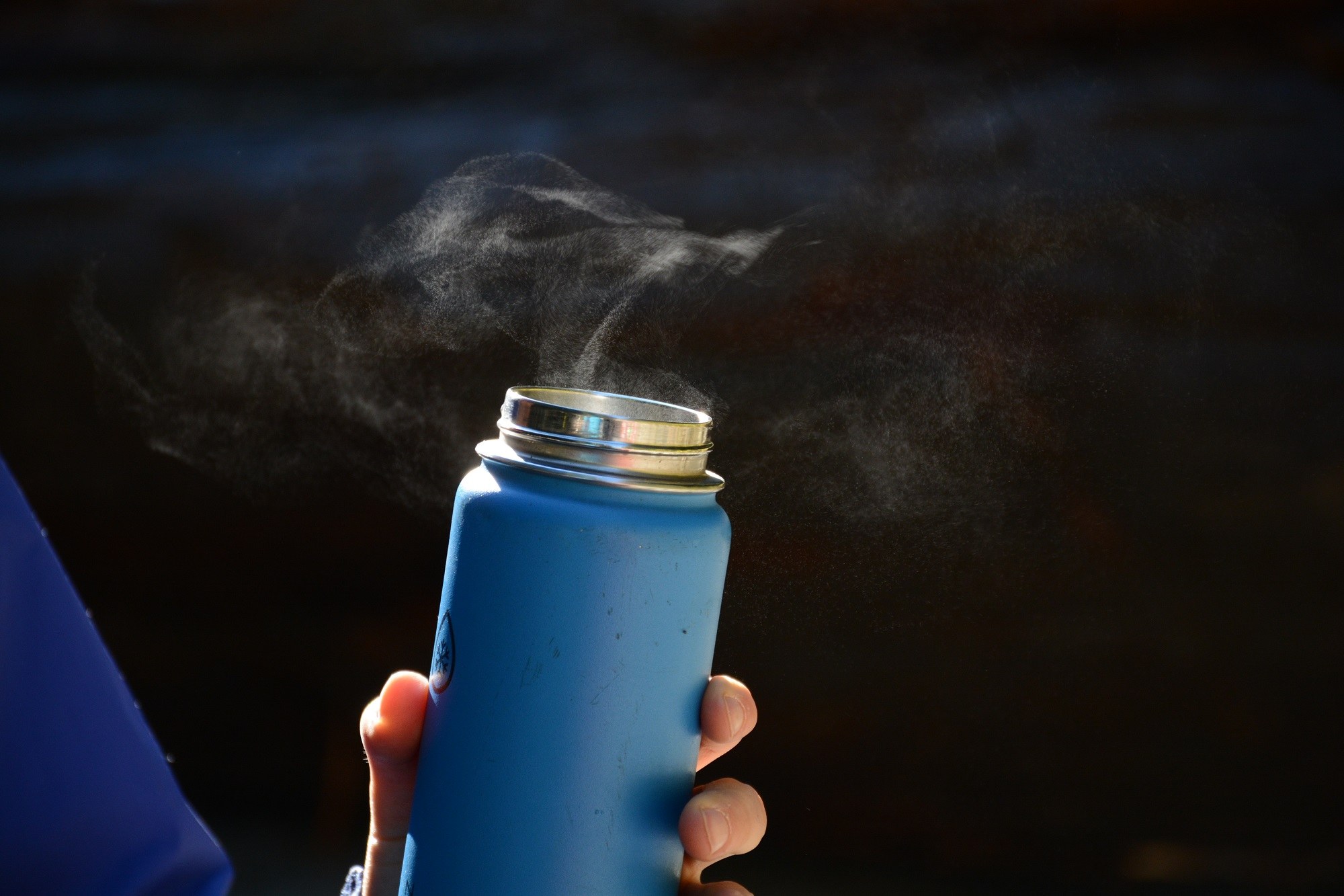 An open thermos lets off steam during a brisk winter hike.
