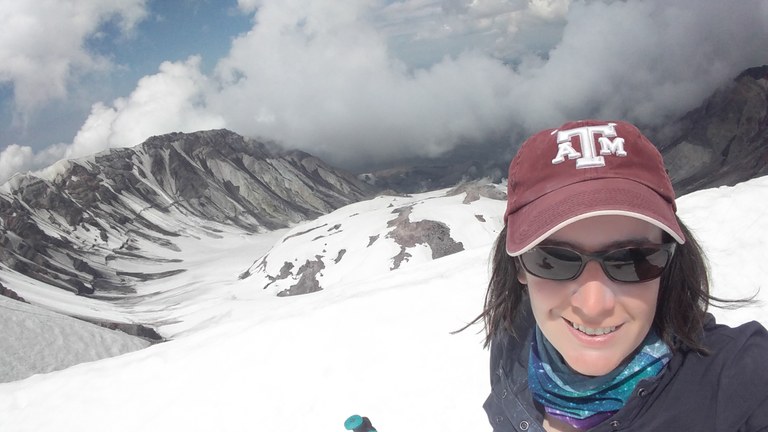 Mount St. Helens climb A hiker wearing sunglasses and a ball cap stands above the crater of Mount St. Helens.