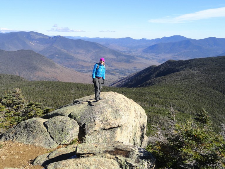 A hiker stands on a scenic outlook in New England.