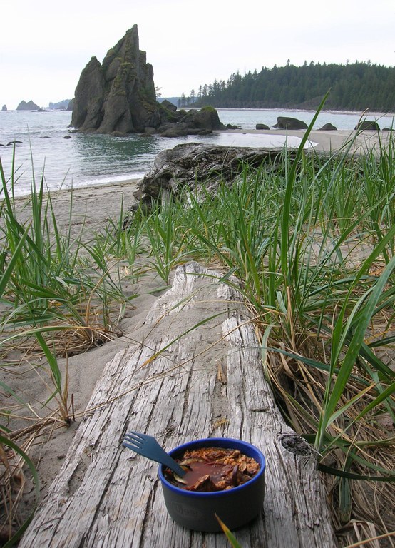 A backcountry meal resting on a piece of driftwood on the Pacific Coast.