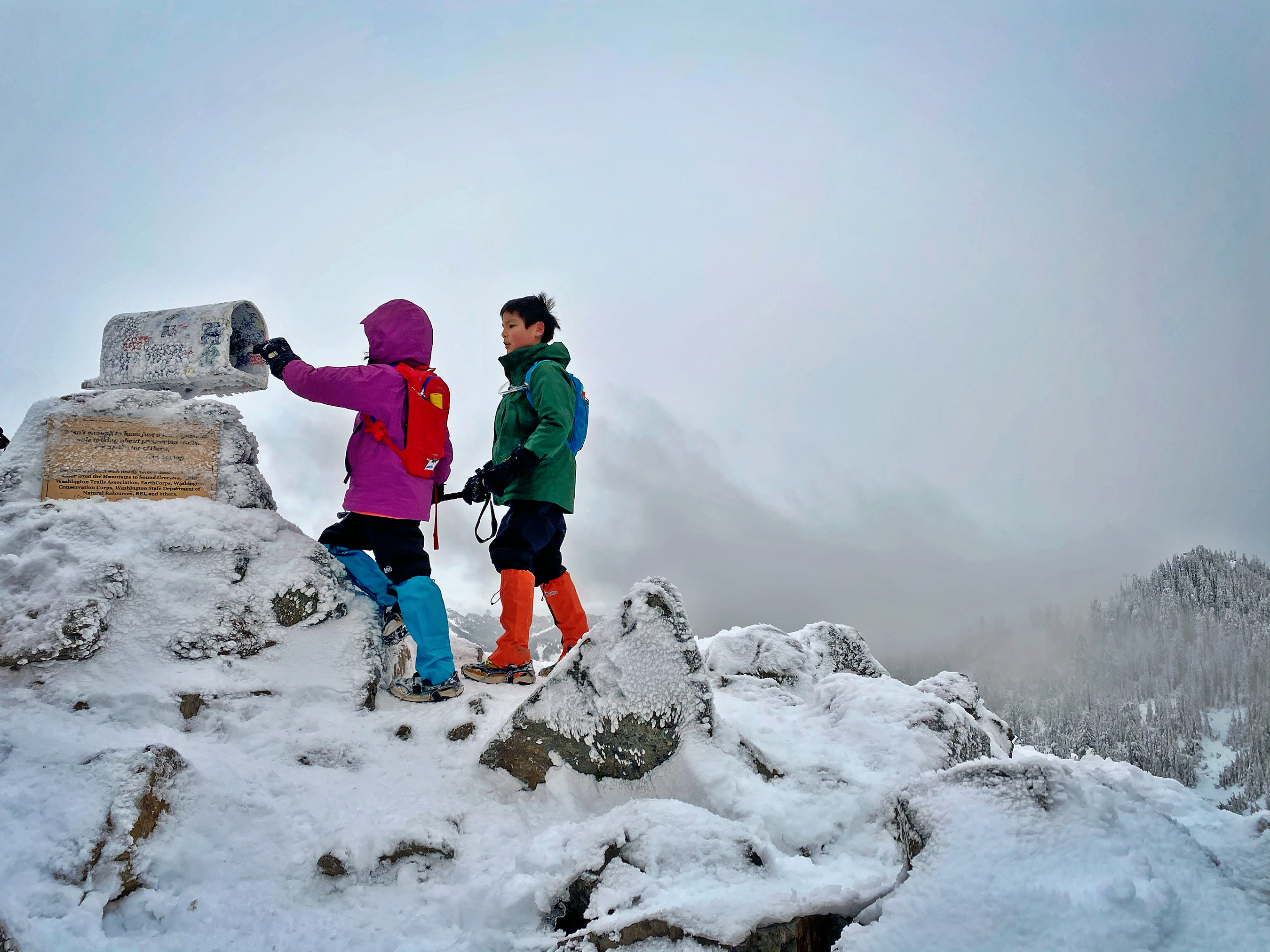 1st hikers in action Yunyan Wang Two young hikers in brightly colored winter clothing look in the mailbox and Mailbox Peak.