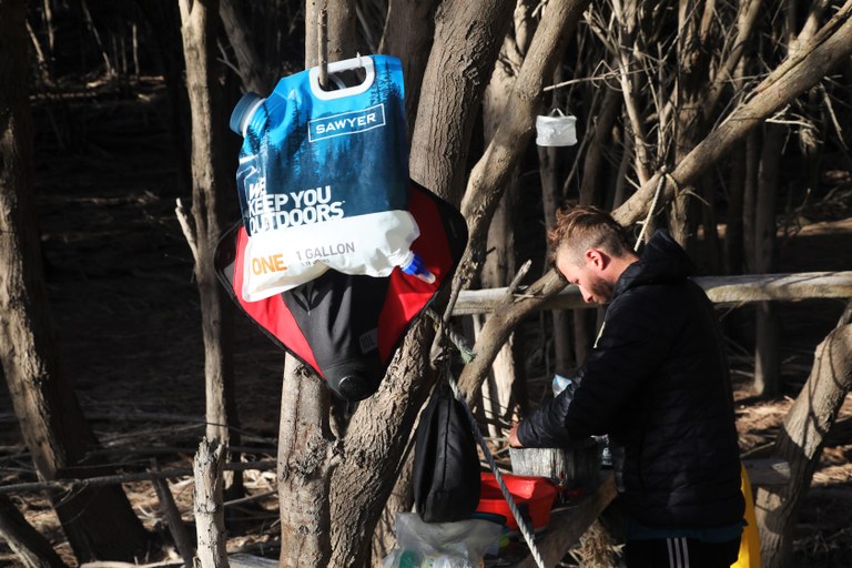 A gravity filter hangs from a tree.