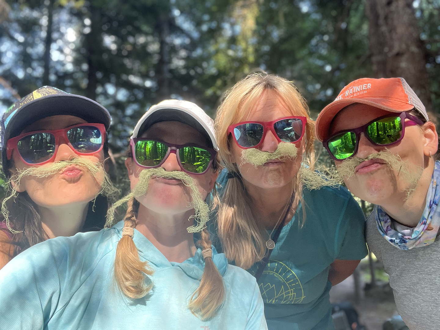 3rd trail family 2024 Erika Ouderkirk A group of hikers smiles at the camera, with moss mustaches.