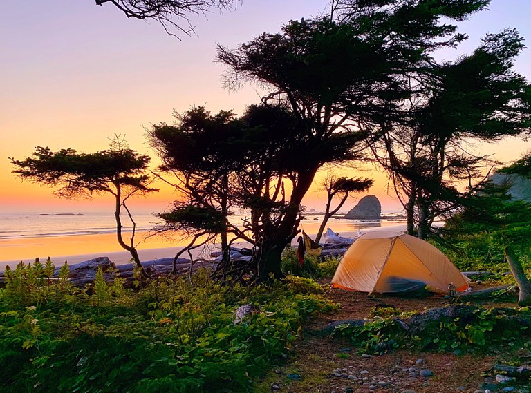 A tent at the beach during the golden hour.