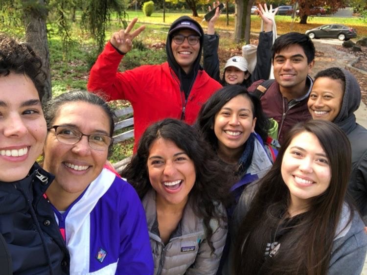 A Latino Outdoors hiking group poses for a selfie in a park.