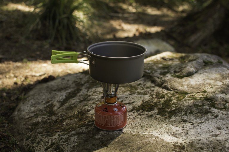A lightweight pot sits on top of a backpacking stove.
