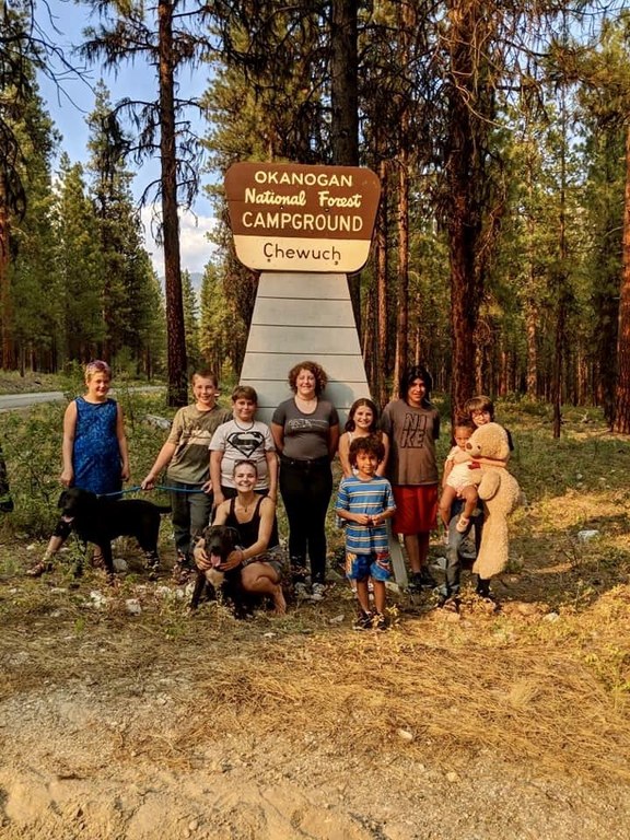 A large group of people stand in front of the Chewuch Campground sign.