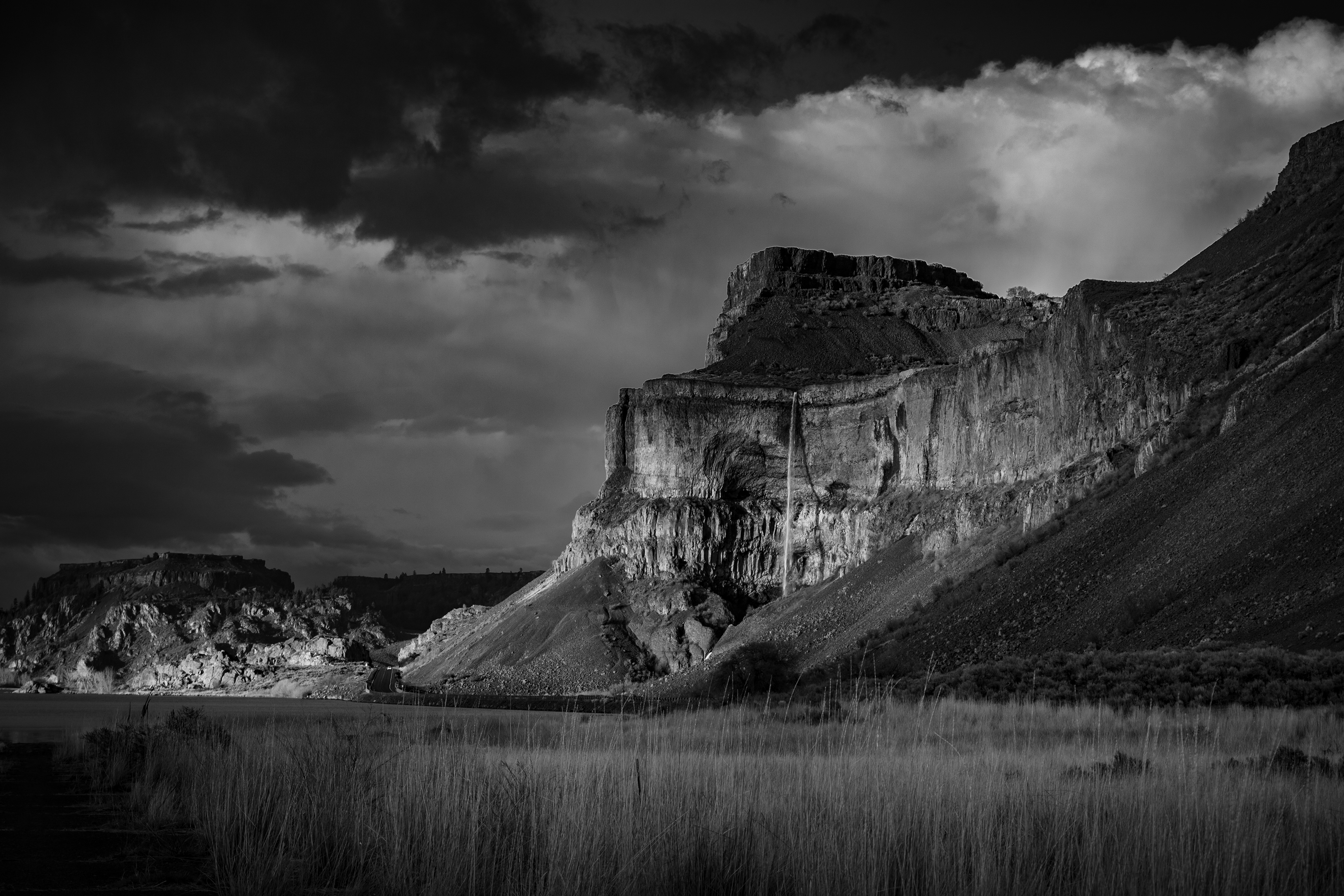 East of Cascades Emily Rehn A waterfall falls over a tall cliff in a dramatic black and white photo.