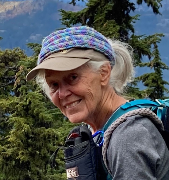 A trail advocate wearing hiking gear smiles at the camera from a wilderness setting.