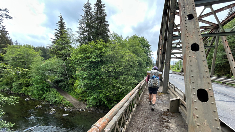A hiker walks along a bridge near Forks, WA.