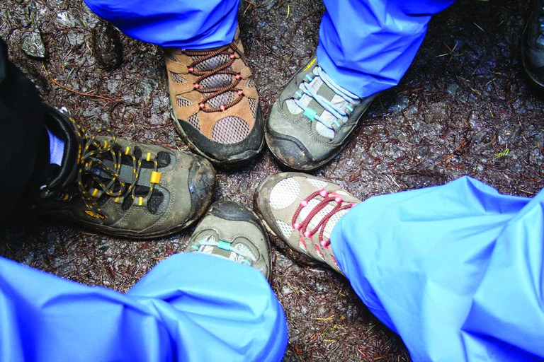 Five shoes point together on trail.