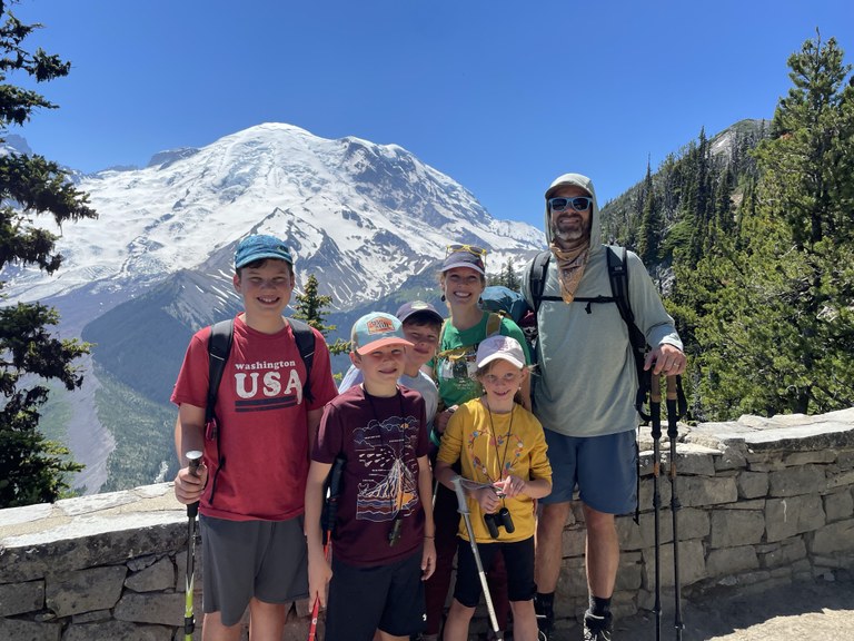 A family of hikers smile from a scenic overlook.