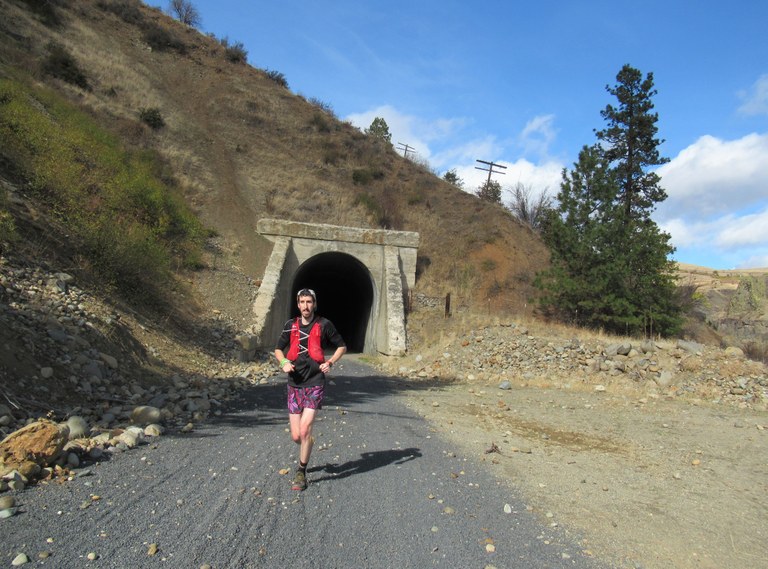 A trail runner runs down a gravel trail.