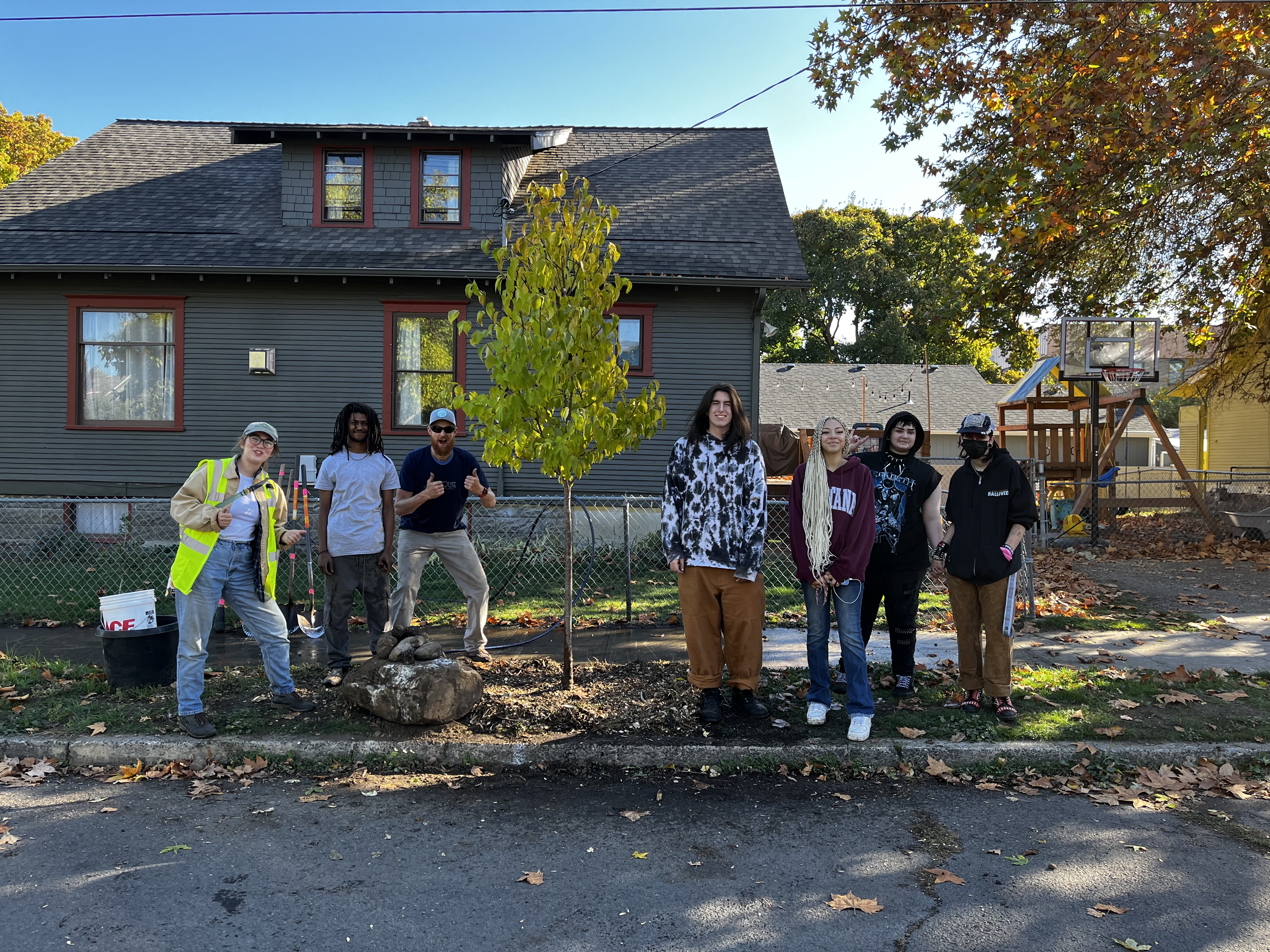 6 volunteers pose next to newly planted tree.