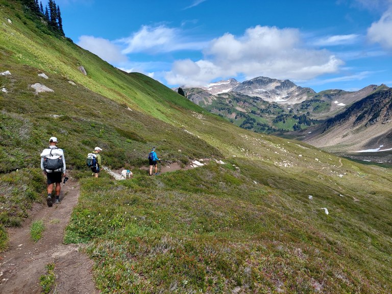 Hikers travel along a grassy ridge along the PCT in Northern Washington.