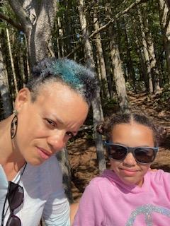Two people smile taking a selfie in the woods.