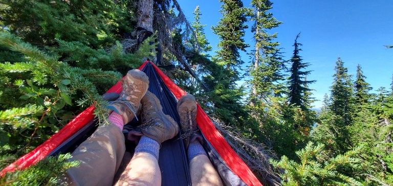 Hikers kick their (socked) feet up in a hammock.