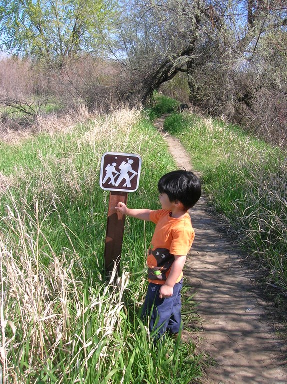 A child stands next to a trail sign.